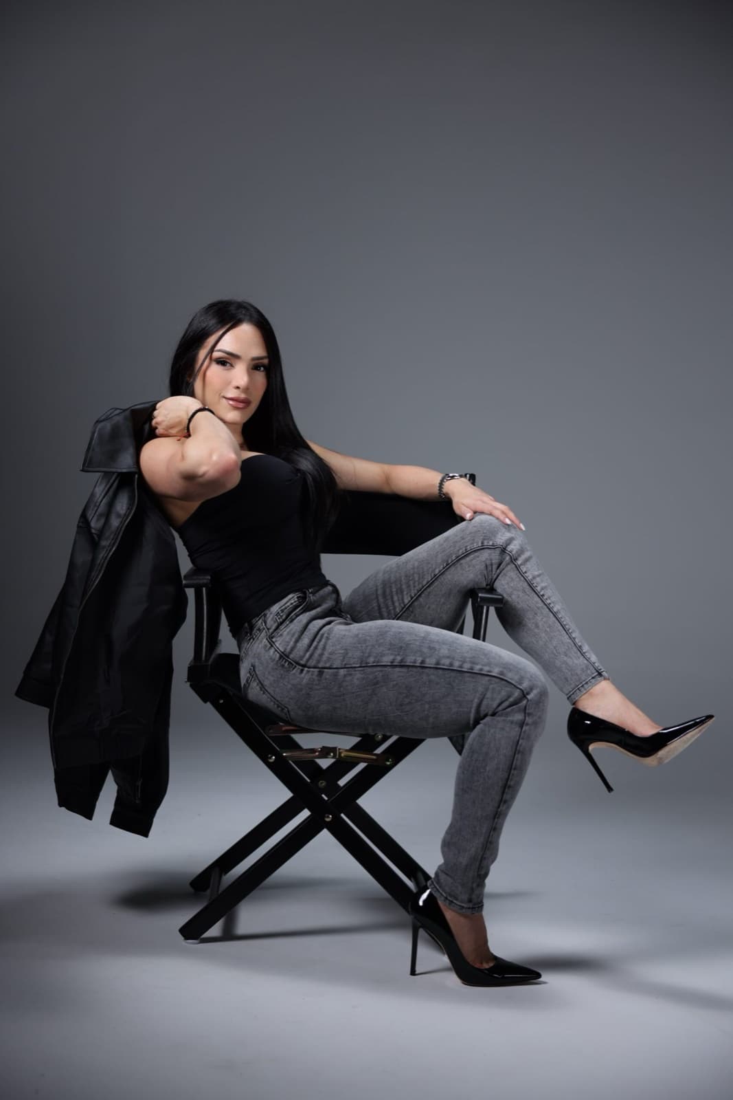 Taneth in a director's chair in a black top and grey jeans