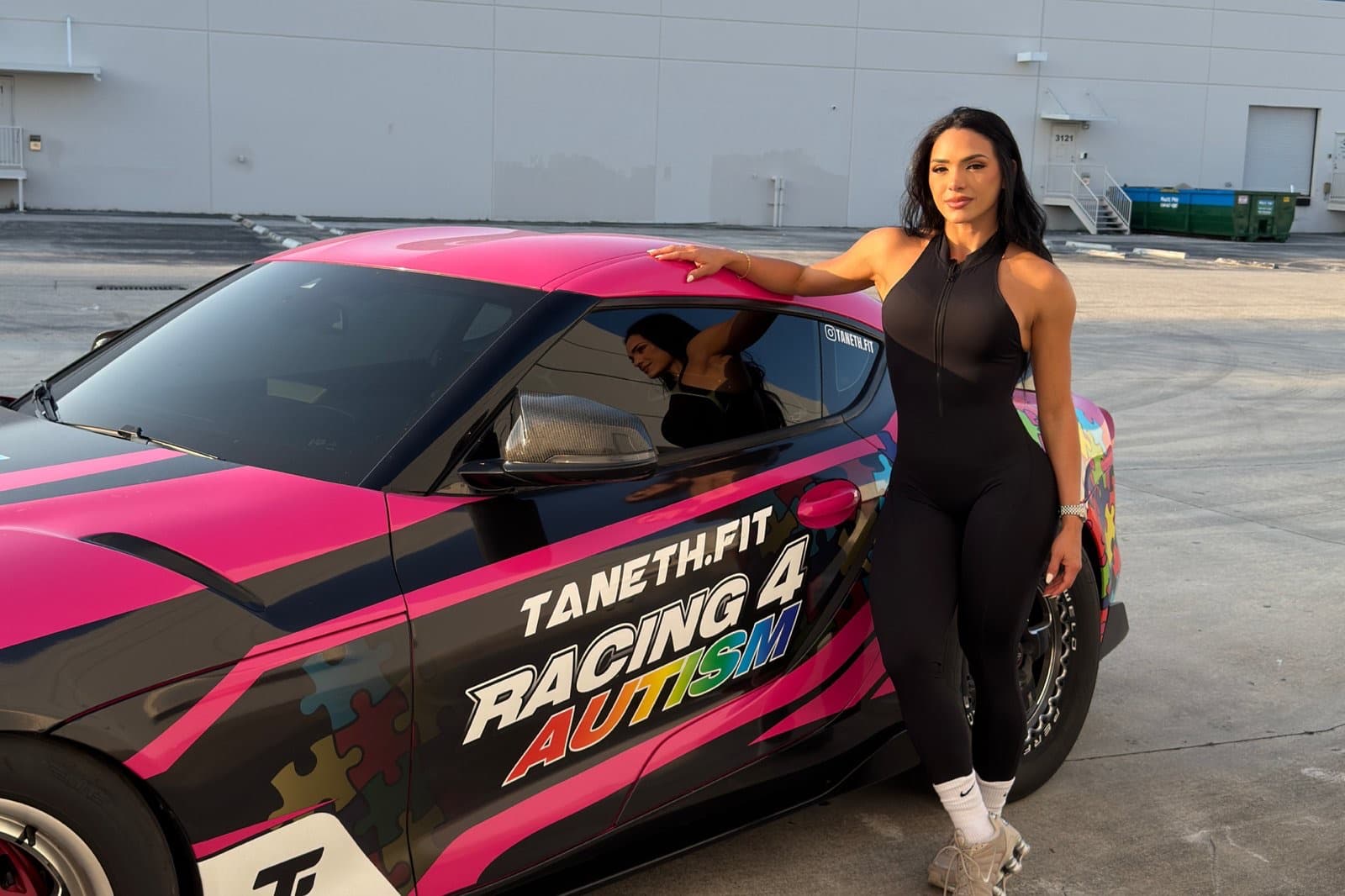 Taneth leaning on her pink and black Toyota Supra